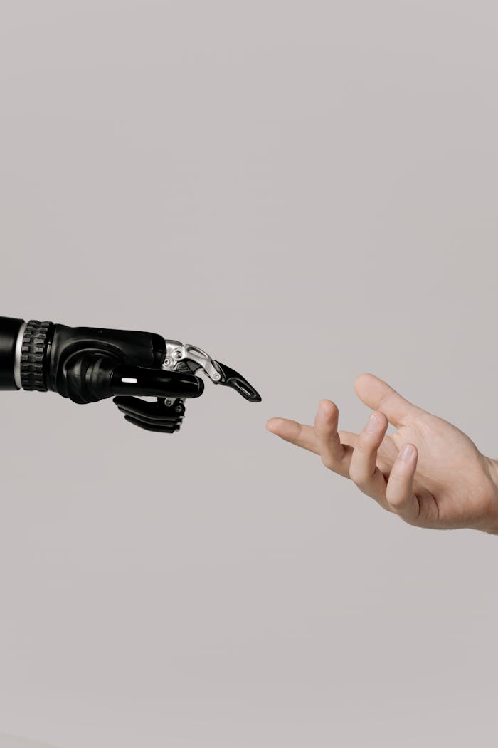 services-04 A human hand reaching to touch a bionic prosthetic hand on a white background.